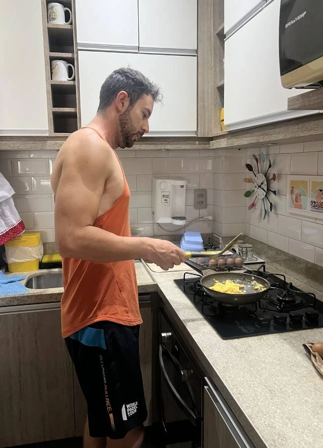 Héctor cocinando en un apartamento de alquiler en Río para ahorrar en el viaje.