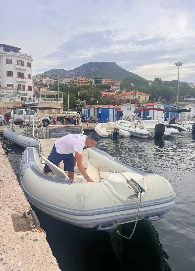 Embarcación semirrígida amarrada en el puerto de un pueblo costero listo para recorrer Cerdeña.