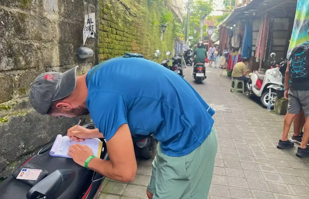 Hombre rellenando formulario en scooter en calle asiática.