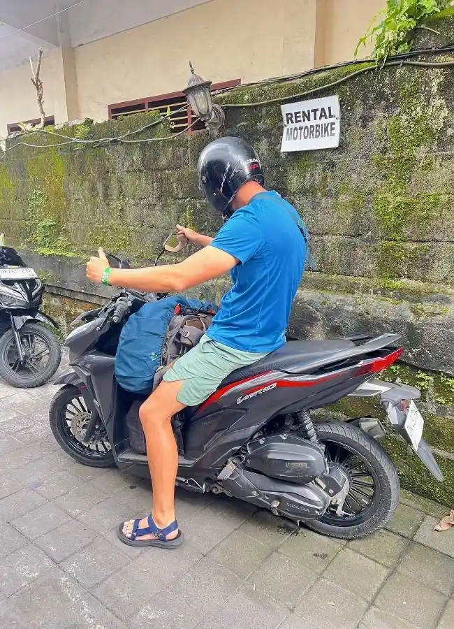Hombre en moto de alquiler con pulgar arriba, listo para viajar.
