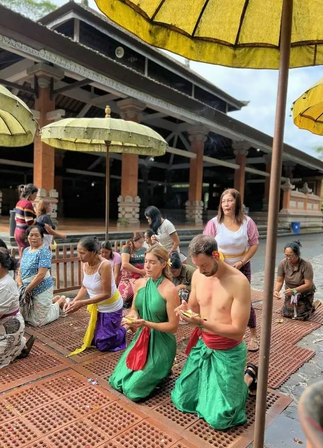 Ceremonia balinesa: personas, incluidos turistas, arrodilladas en templo.