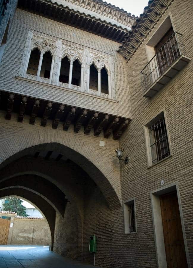 Arquitectura histórica española con arcos, ventana ornamentada y balcón.