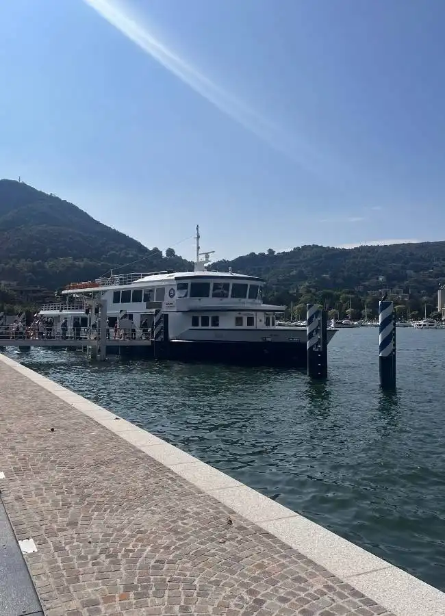 Ferry en lago montañoso bajo cielo azul soleado.