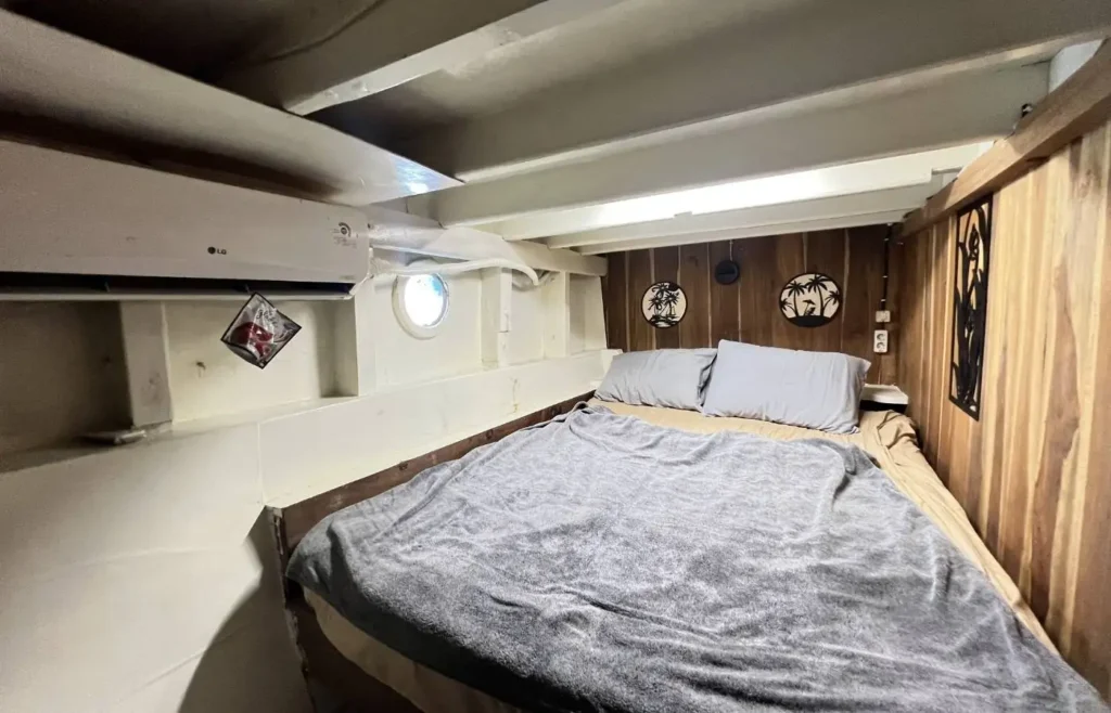 Acogedor dormitorio de barco con cama y decoraciones de palmeras.