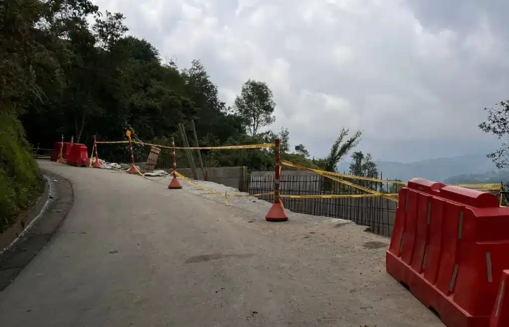 Carretera de montaña con obras, vallas y cinta de precaución.