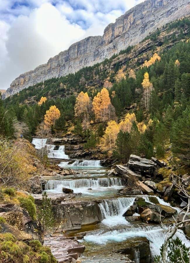 El río Arazas fluyendo entre rocas con los colores vibrantes del otoño en el Valle de Ordesa.