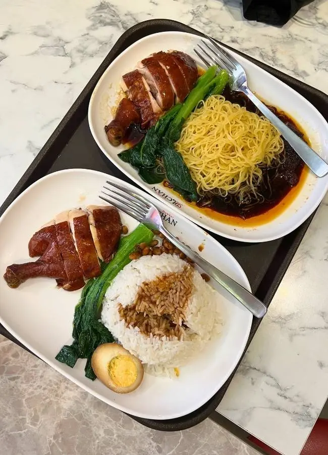 Dos platos de pollo asado, arroz y fideos asiáticos.