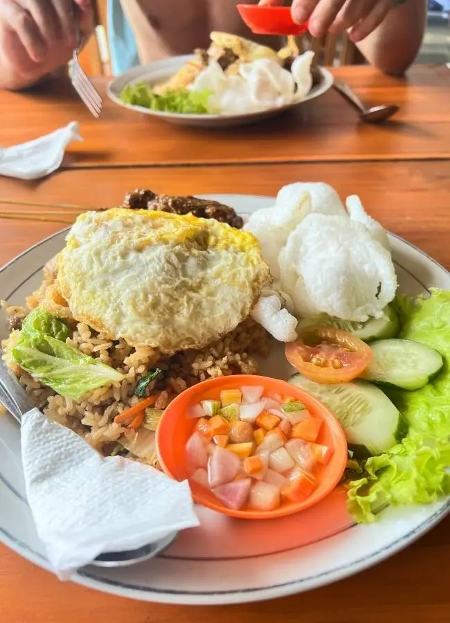Plato de comida local con arroz, carne y verduras en un warung de Indonesia.