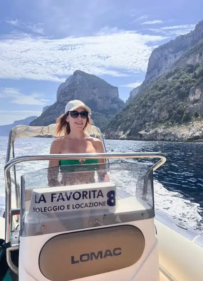 Mireia sentada al timón de la lancha motora de alquiler en el Golfo de Orosei.