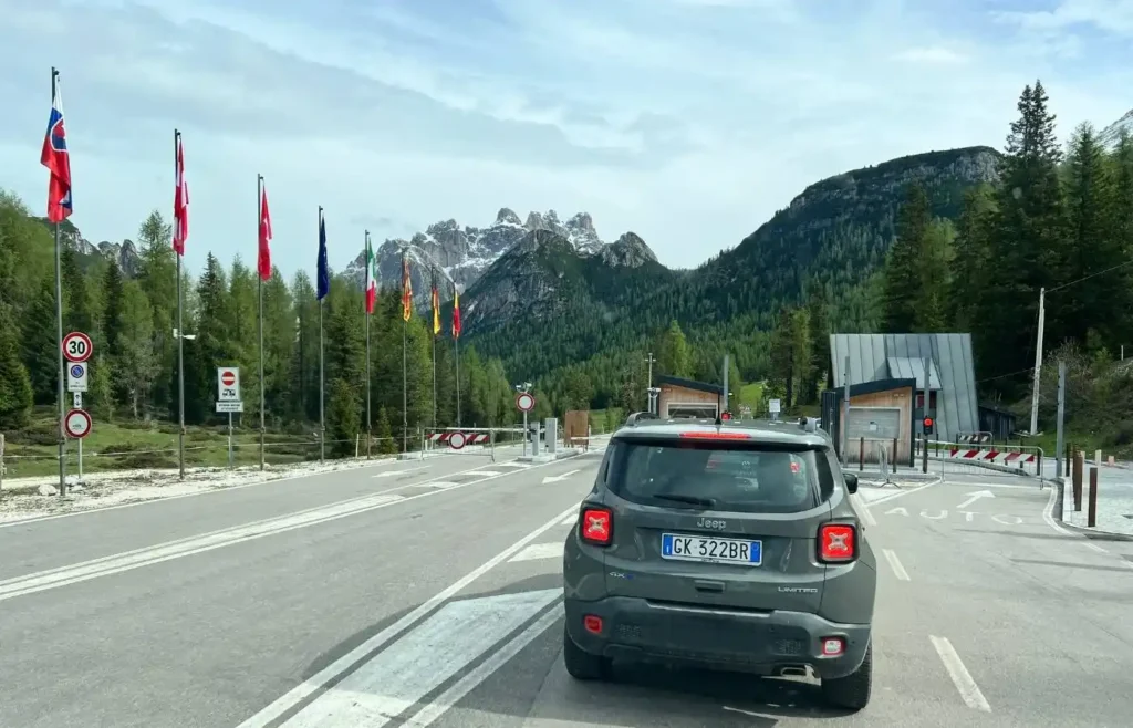Coche circulando por una carretera panorámica entre las montañas de Dolomitas.