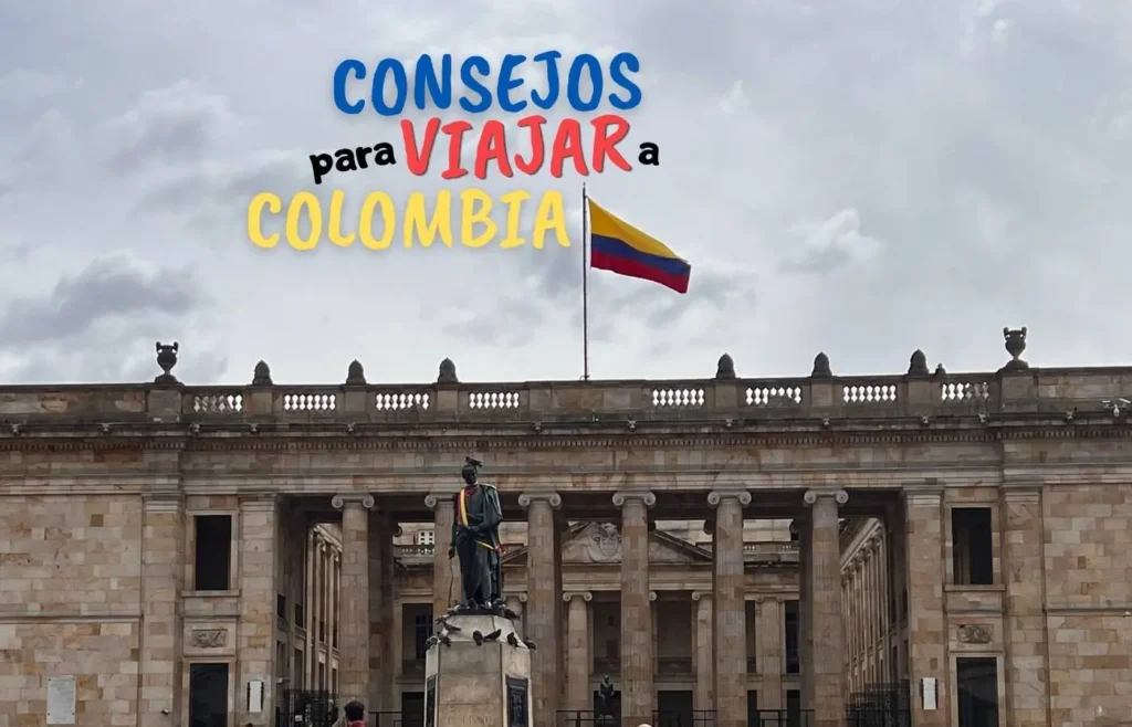 Bandera colombiana ondeando sobre un edificio histórico con estatua.