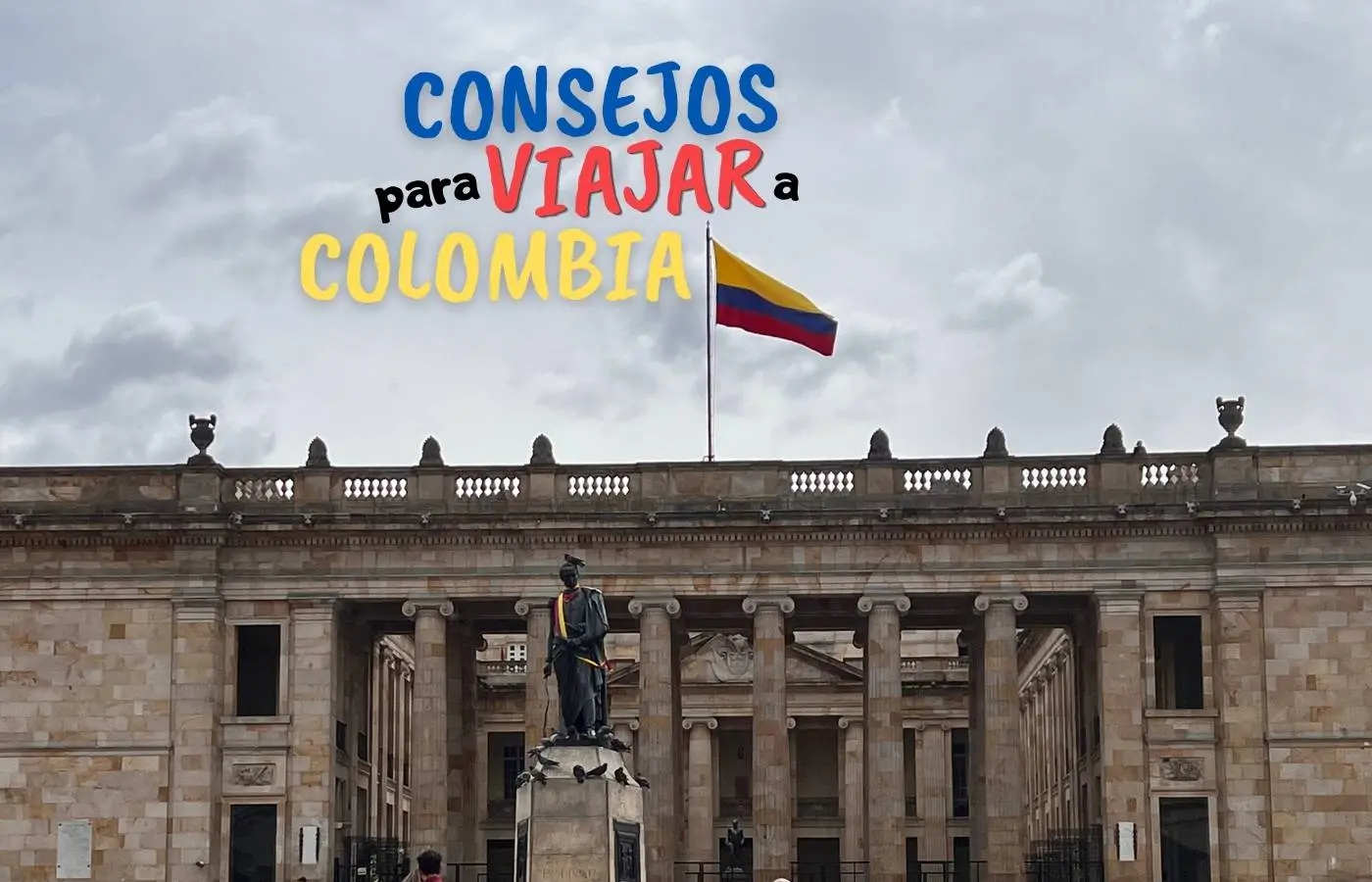 Bandera colombiana ondeando sobre un edificio histórico con estatua.