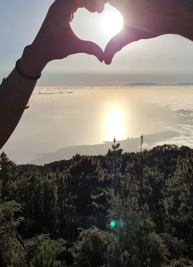Silueta de manos formando un corazón con el atardecer de fondo en Tenerife.