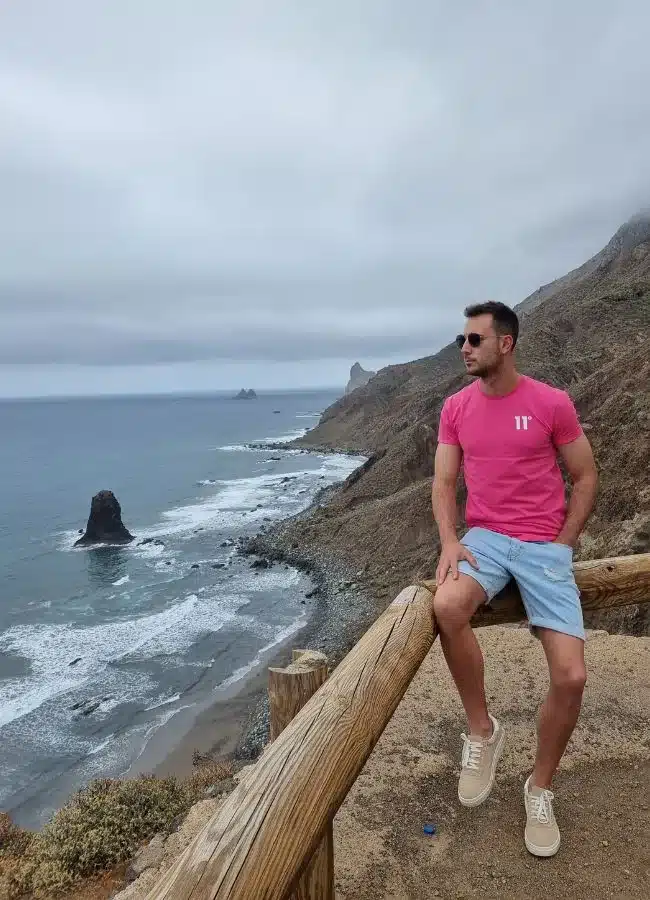 Turista sentado frente a los acantilados y la costa salvaje del norte de Tenerife.