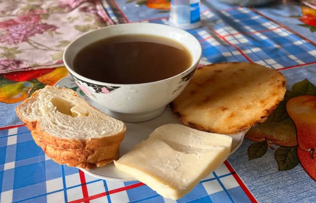 Taza de aguapanela caliente acompañada de queso, arepa y pan, comida típica en la ruta a Toche.