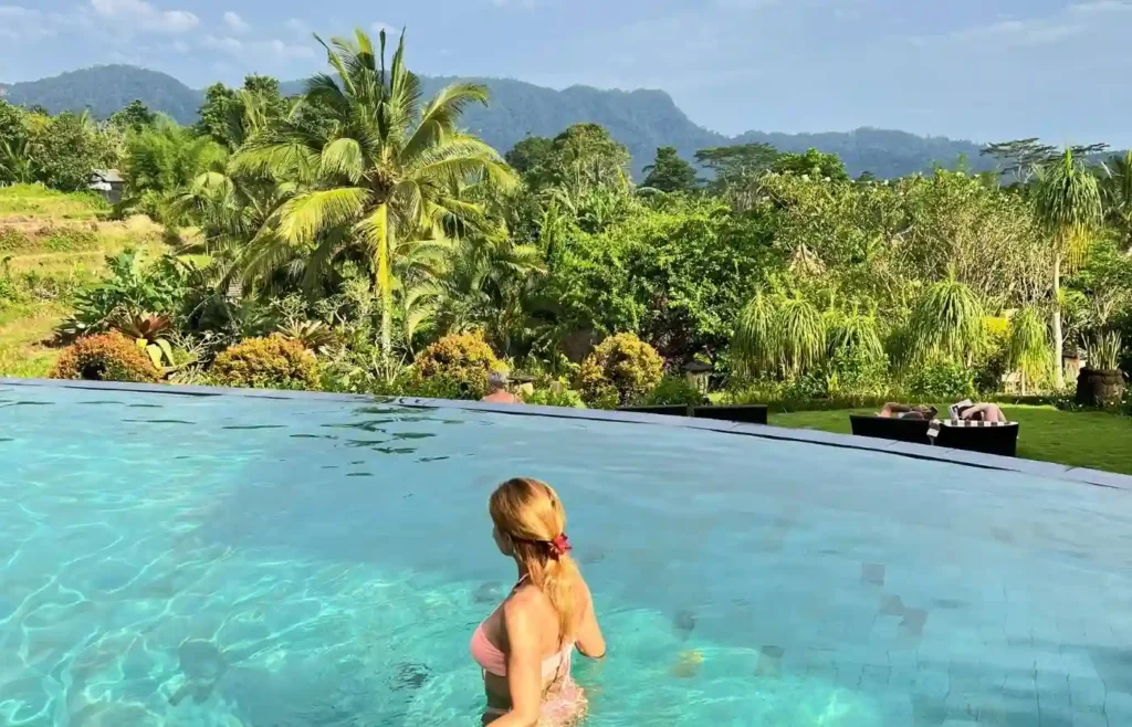 Mujer en una piscina infinita con vistas a la naturaleza en un hotel con encanto en Bali.