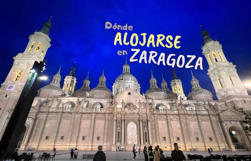 Basílica del Pilar iluminada de noche, texto 'Dónde ALOJARSE en ZARAGOZA'.