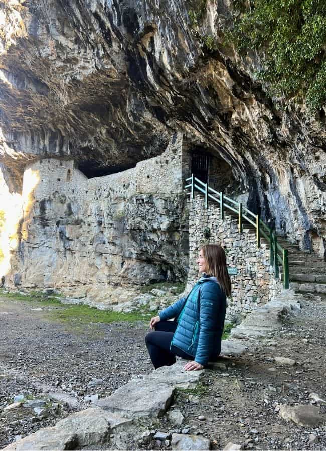 Mujer sentada junto a la pared de roca de la ermita de San Urbez, integrada en el Cañón de Añisclo.