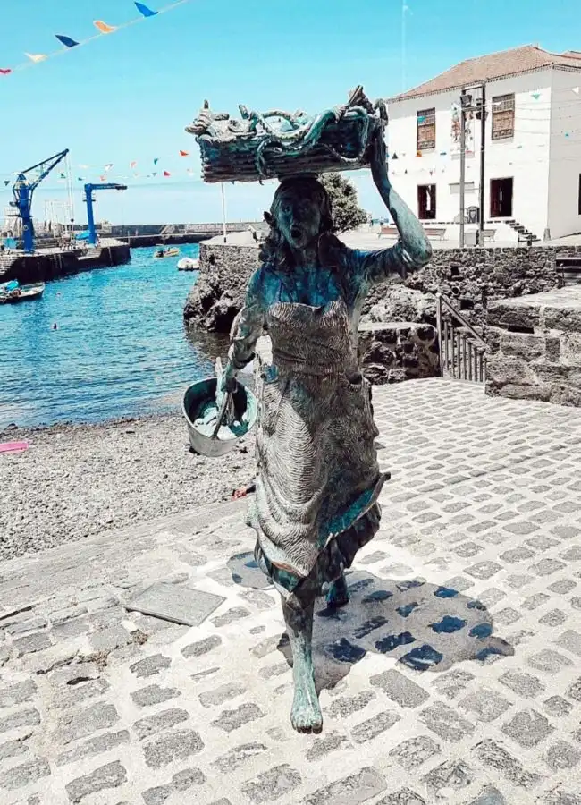 Estatua de bronce de una mujer pescadora en el puerto de una ciudad canaria.