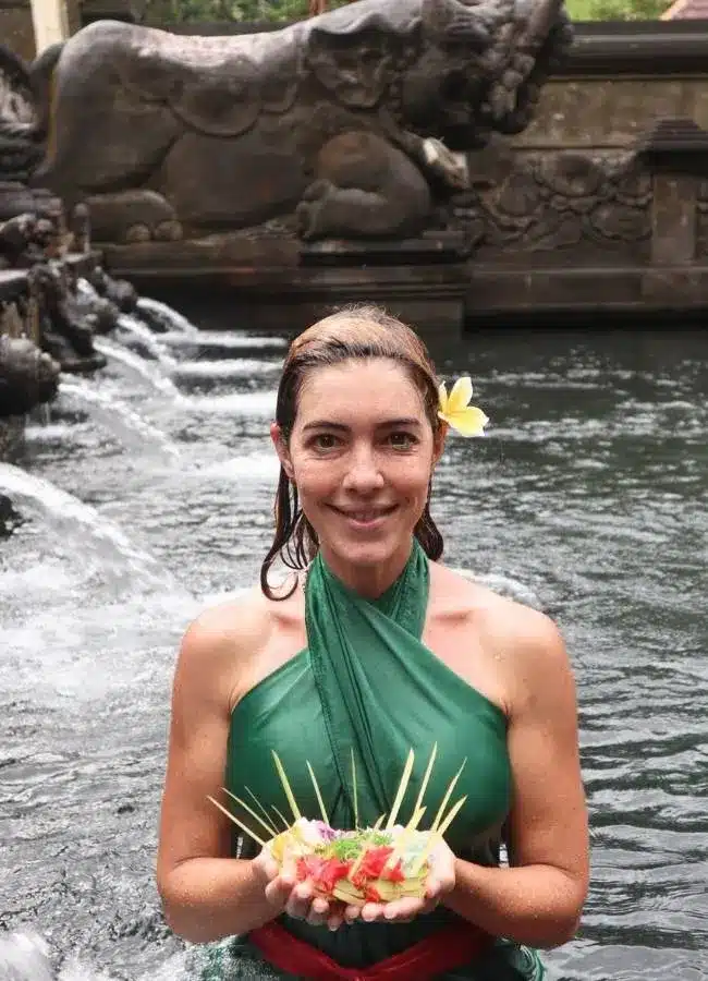 Mujer viajera sonriente con ofrenda en templo de agua.