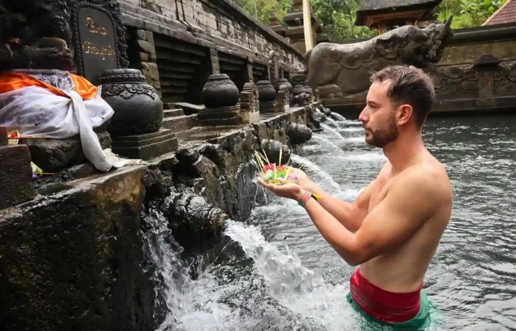 Viajero recibiendo el agua sagrada en los manantiales de un templo balinés.
