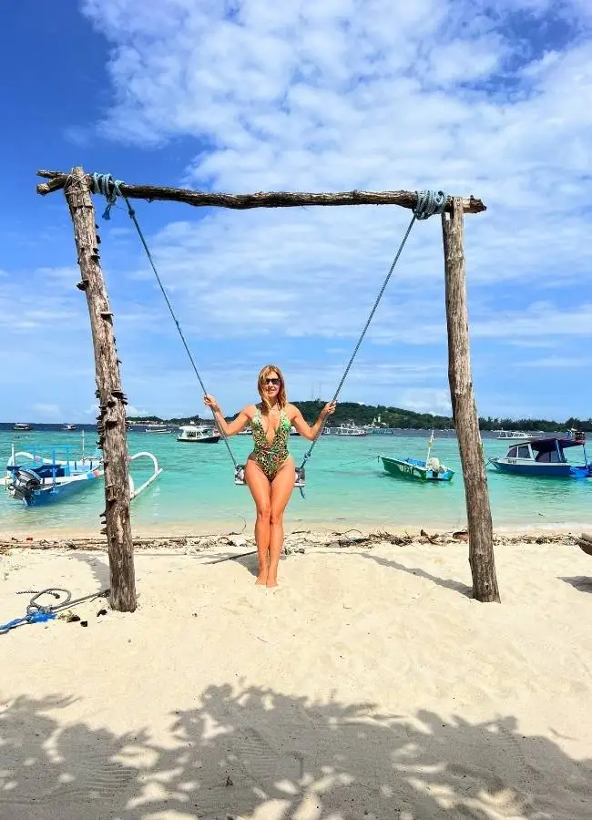 Viajera de espaldas en el icónico columpio de madera dentro del agua en una playa de las islas Gili.