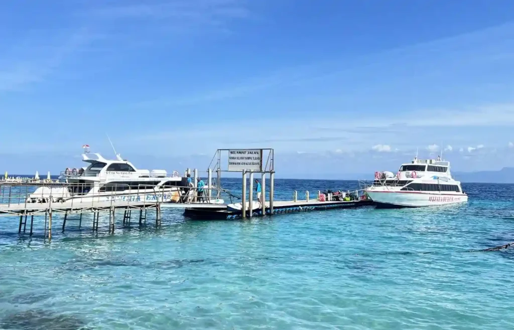 Muelle con barcos en agua turquesa bajo cielo azul.