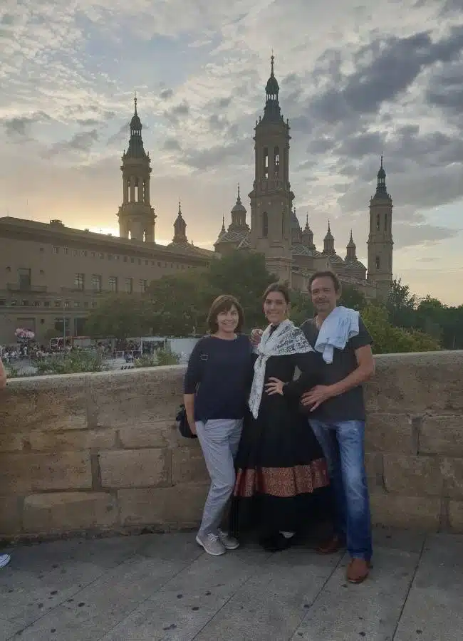 Familia con vestimenta tradicional ante la Basílica del Pilar al atardecer.