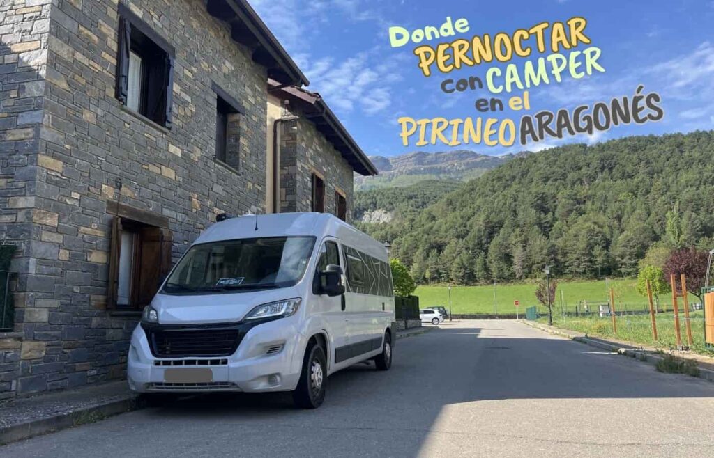 Furgoneta camper aparcada junto a una casa tradicional de piedra en Fiscal bajo un cielo azul.