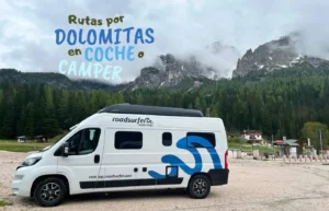 Furgoneta camper blanca estacionada durante un viaje por carretera en las Dolomitas.