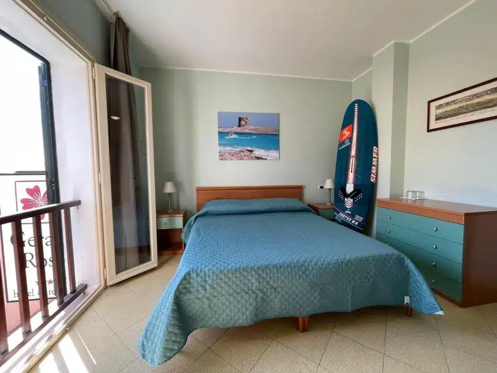 Fachada y habitaciones del Hotel Geranio Rosso en el centro de Stintino, una opción de alojamiento económico para visitar la playa de La Pelosa.