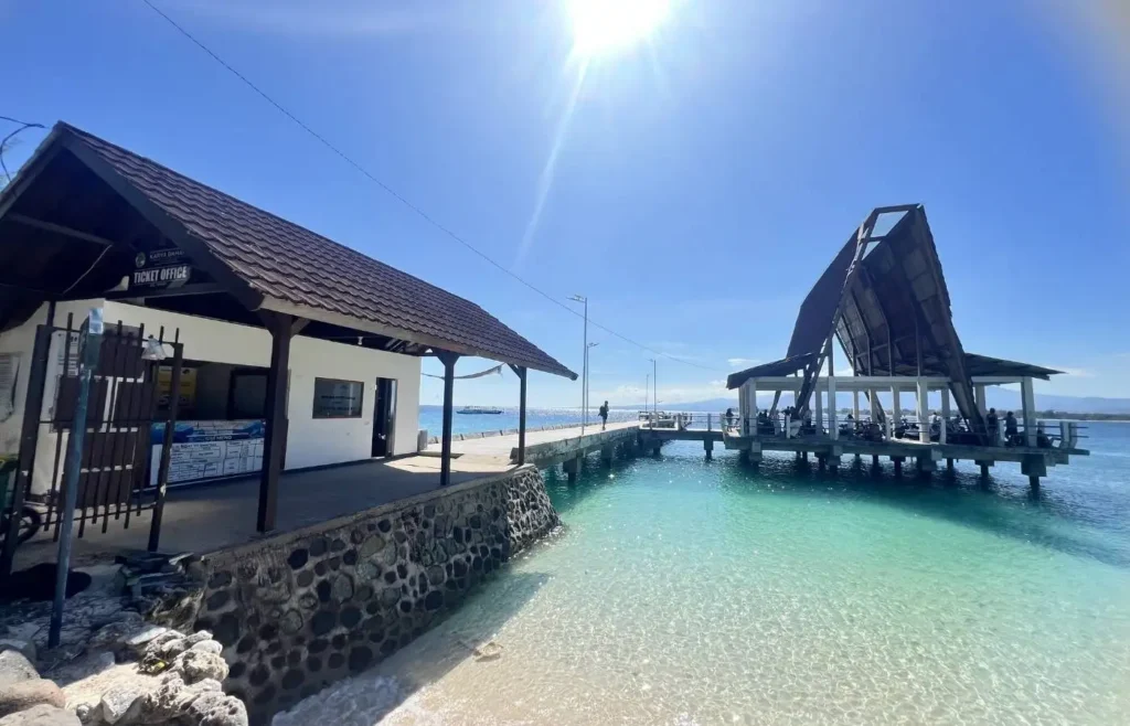 Muelle tropical, aguas cristalinas, oficina billetes, edificio original bajo sol.