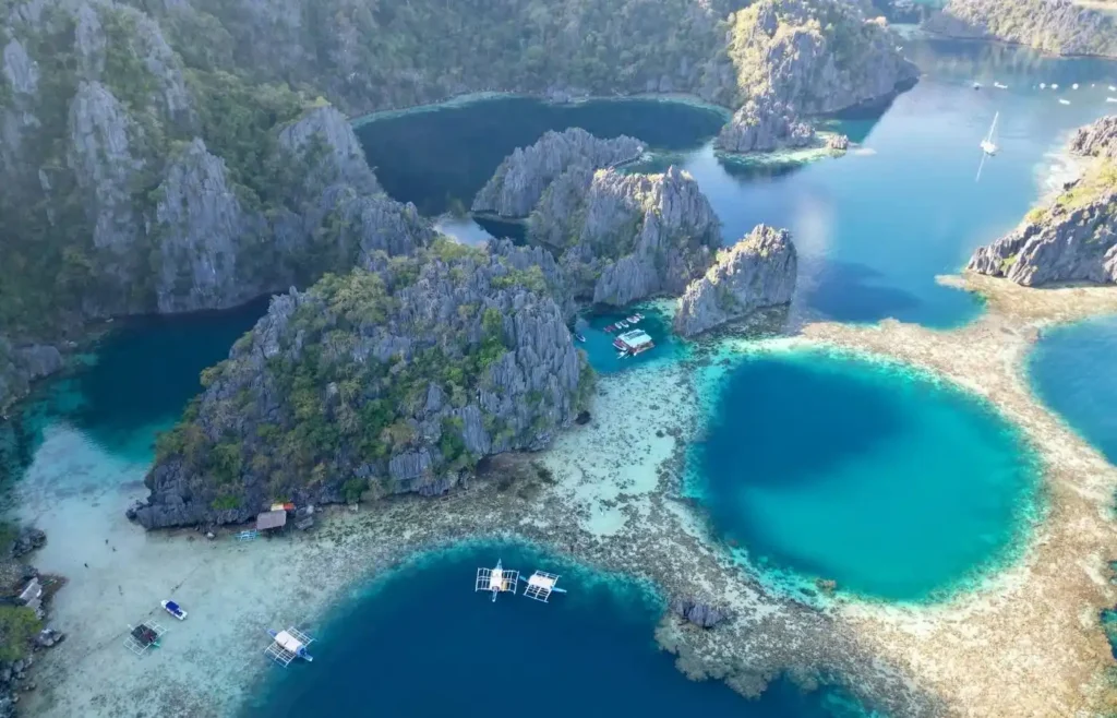 Vista aérea lagunas tropicales, acantilados calizos, aguas turquesas y arrecifes.