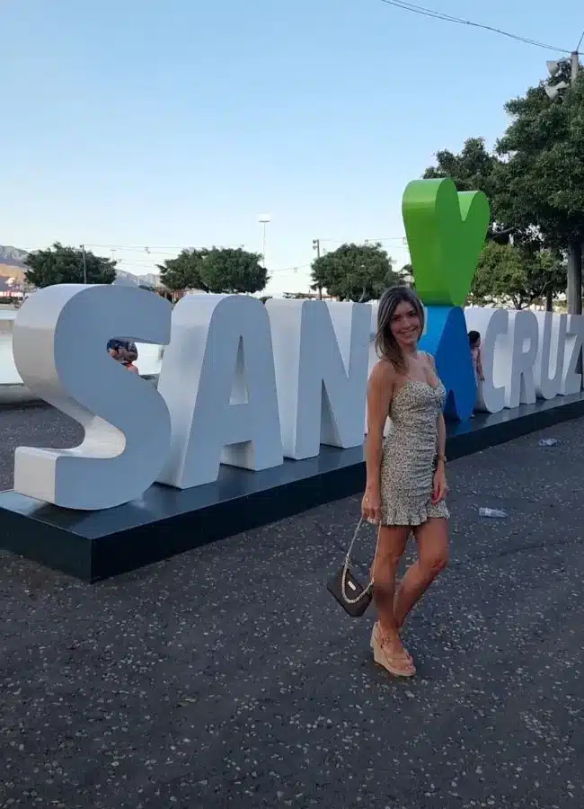 Mujer posando de noche junto al letrero iluminado de Santa Cruz de Tenerife.