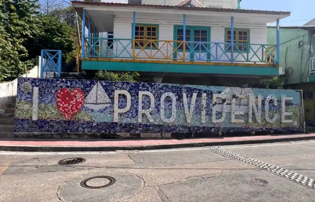 Mosaico 'I ❤️ Providence' con casa caribeña colorida.