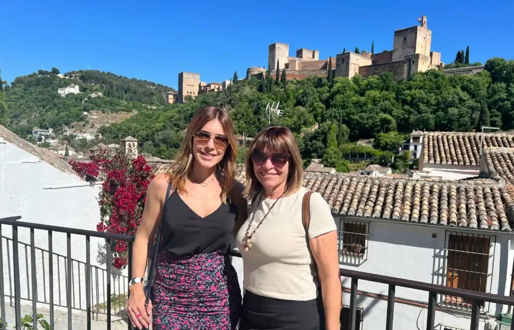 Dos mujeres posando en un mirador con la fortaleza de la Alhambra y Sierra Nevada detrás.