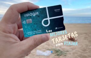 Mano sosteniendo tarjeta bancaria para viajar en un paisaje internacional.