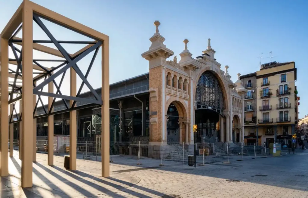 Mercado antiguo con estructura moderna bajo cielo azul soleado.