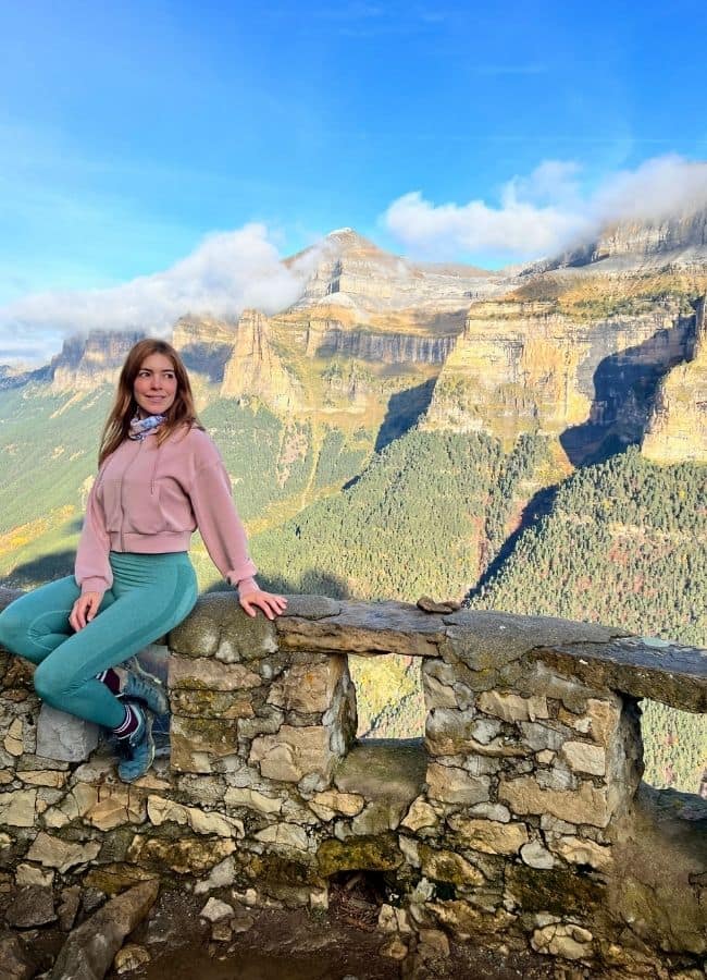Mujer sentada en el murete del mirador de Calcilarruego tras subir la Senda de los Cazadores.