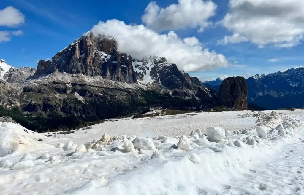 Majestuosas montañas nevadas con nubes bajo cielo azul.
