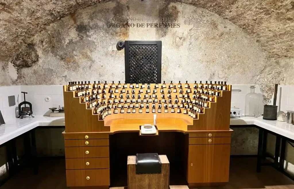 Estantería semicircular de madera con cientos de pequeños frascos de esencia en un laboratorio de perfumes.
