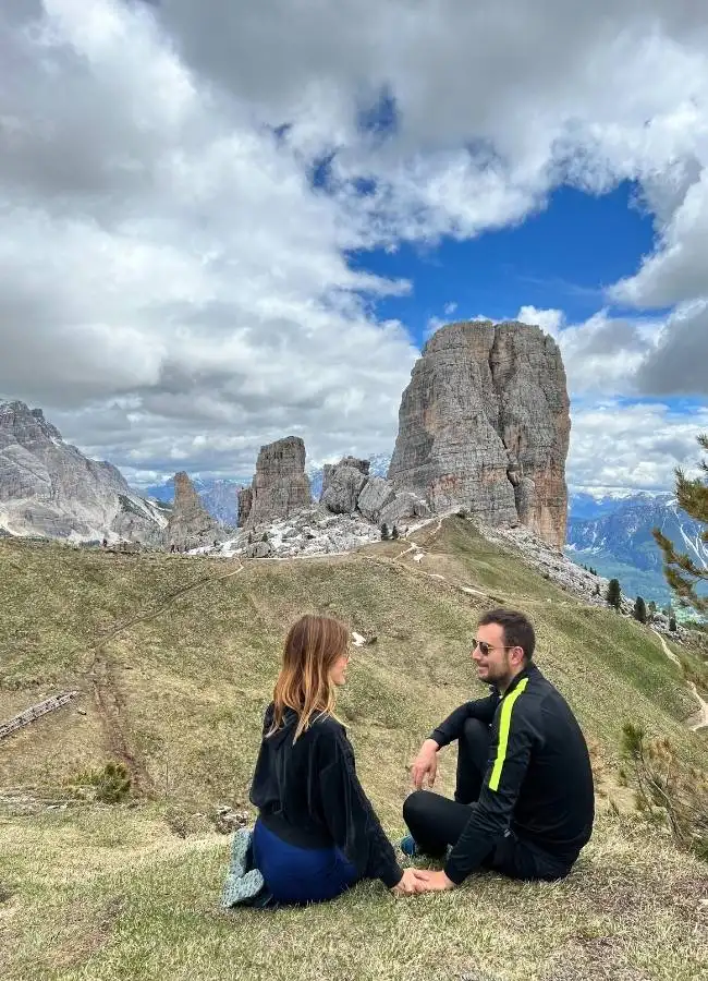 Pareja sentada en la hierba frente a las impresionantes Cinque Torri.