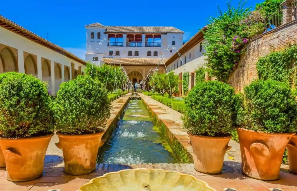Surtidores de agua y setos en el Patio de la Acequia del Generalife con pabellón al fondo.