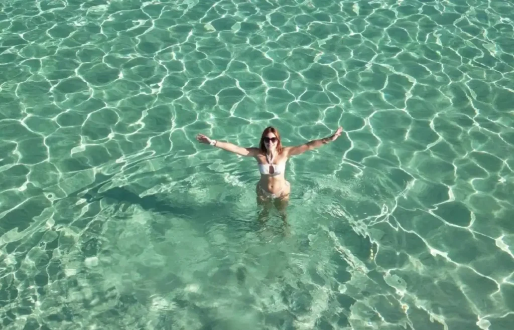 Mujer en bikini blanco flotando en agua turquesa cristalina.