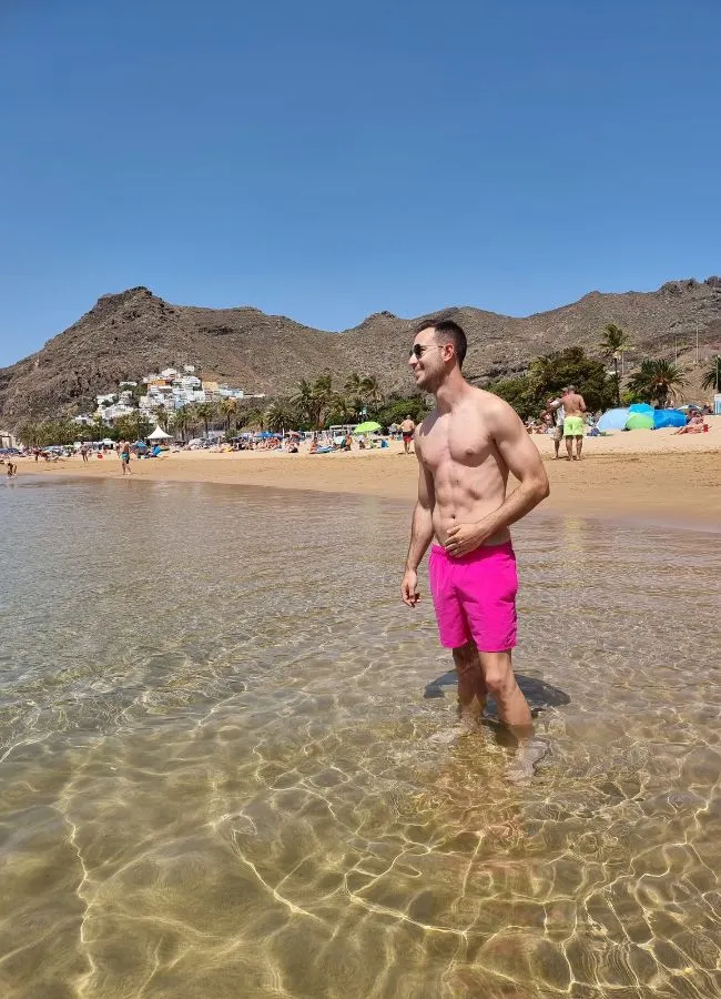 Hombre en bañador rosa caminando por la orilla de la Playa de Las Teresitas en Tenerife.