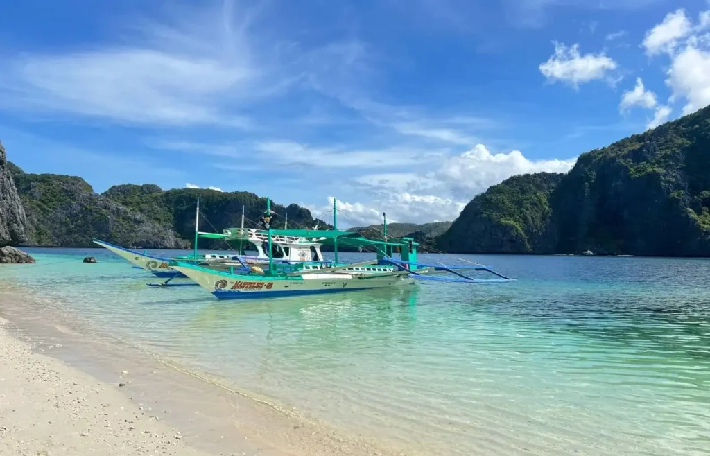 Barco tradicional filipino bangka flotando en el agua cristalina de una playa tropical en Corón.