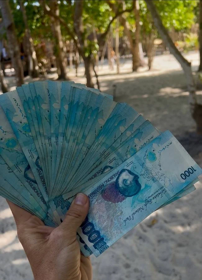Mano sosteniendo un fajo de billetes de pesos filipinos (moneda local).