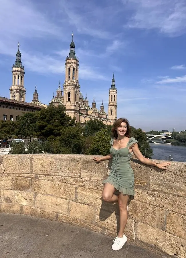 Mujer sonriente con vestido verde ante Basílica del Pilar, Zaragoza.