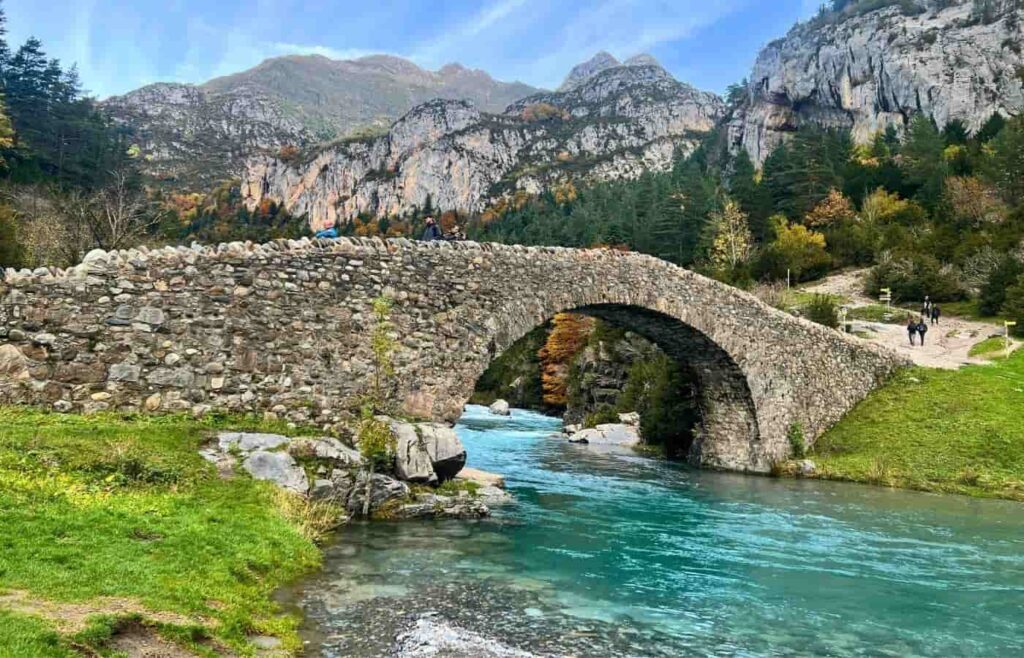 El histórico puente románico de Bujaruelo cruzando el río Ara en otoño.