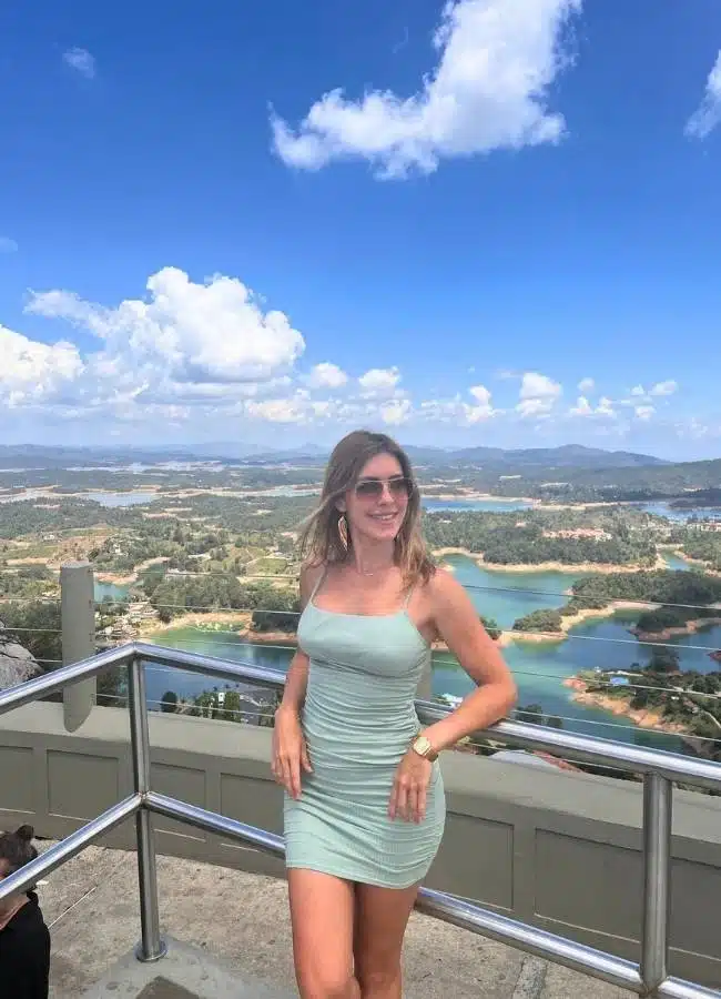 Mujer sonriente en vestido mint con vistas panorámicas a lagos.
